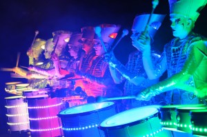Spark! street drumming performers lit up in multiple colours