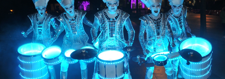 Spark! street drumming performers illuminated in blue light